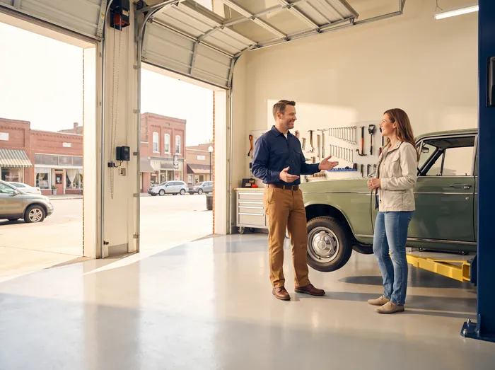 A shop owner talking with a customer in a bright independent auto service bay